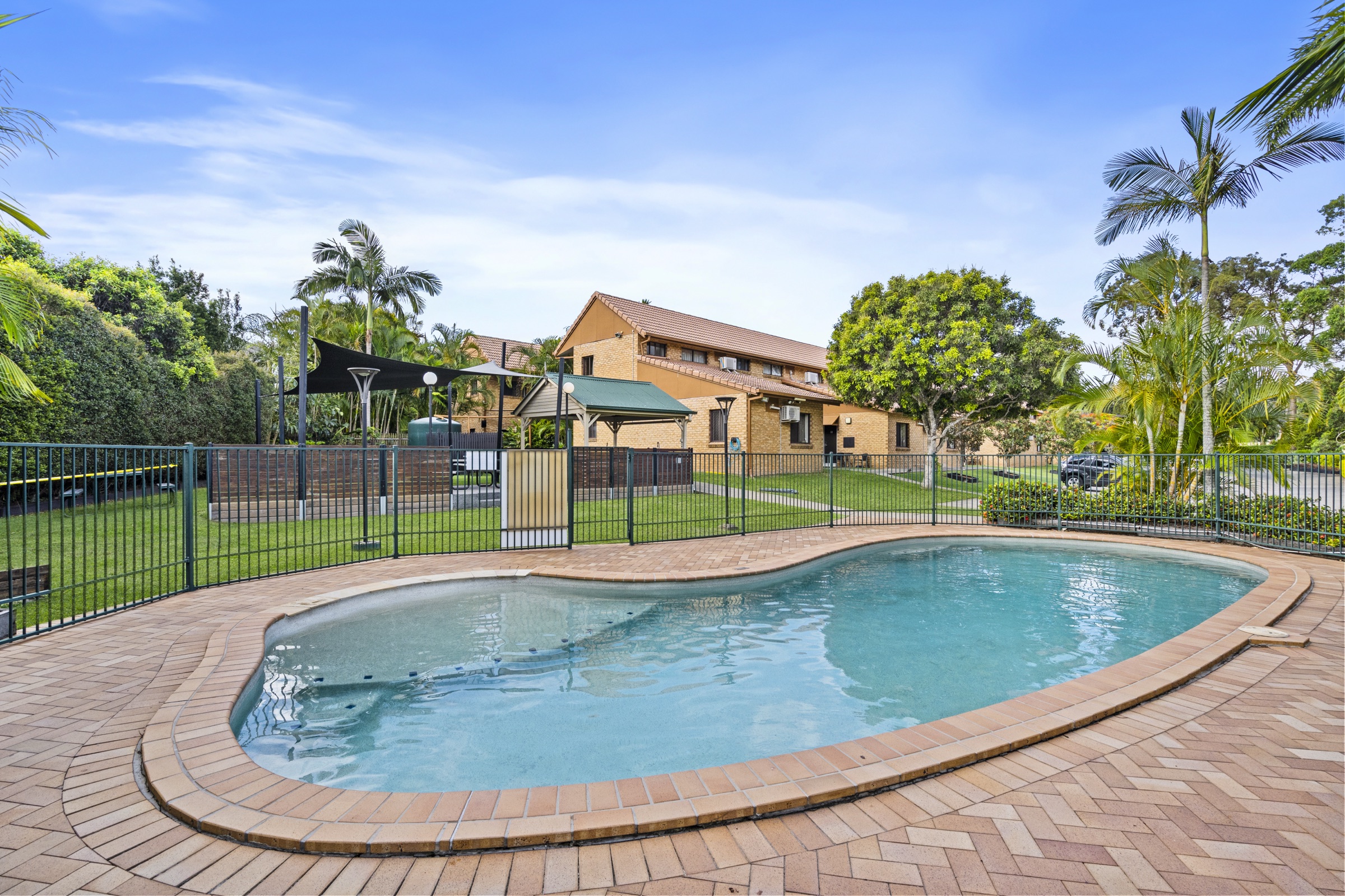 The outdoor swimming pool surrounded by gardens and palms